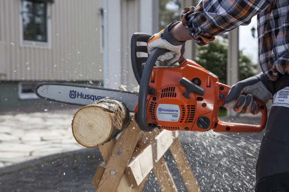 Husqvarna 120 Mark II láncfűrész farönk vágása közben, vágásvédelmes kesztyűben – az új gép első tankjai