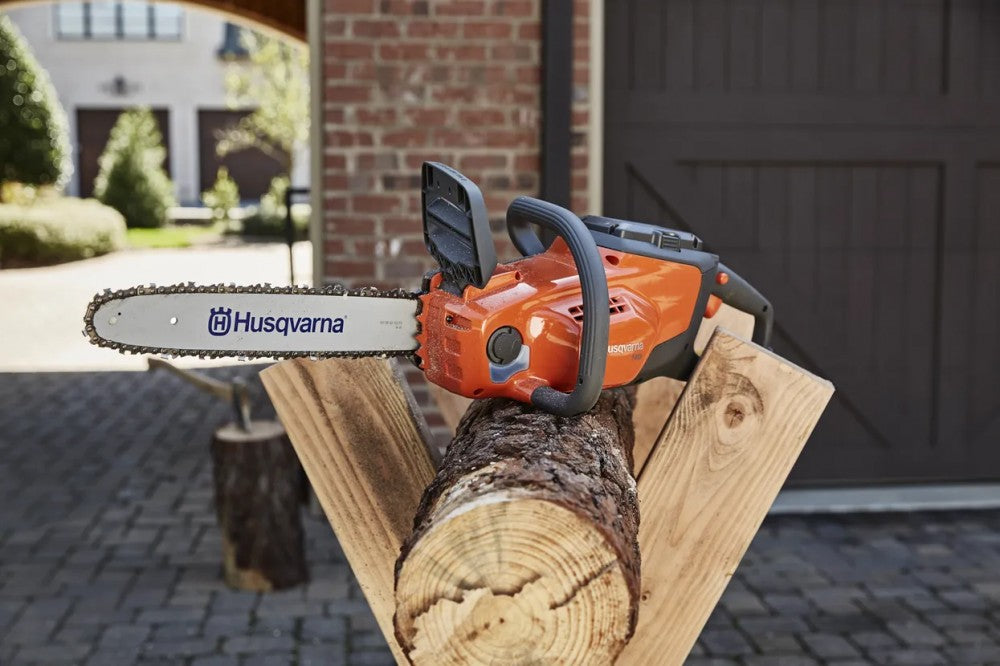 Husqvarna 120i akkus láncfűrésszel rönköt daraboló felhasználó fűrészbakon, ház előtt
