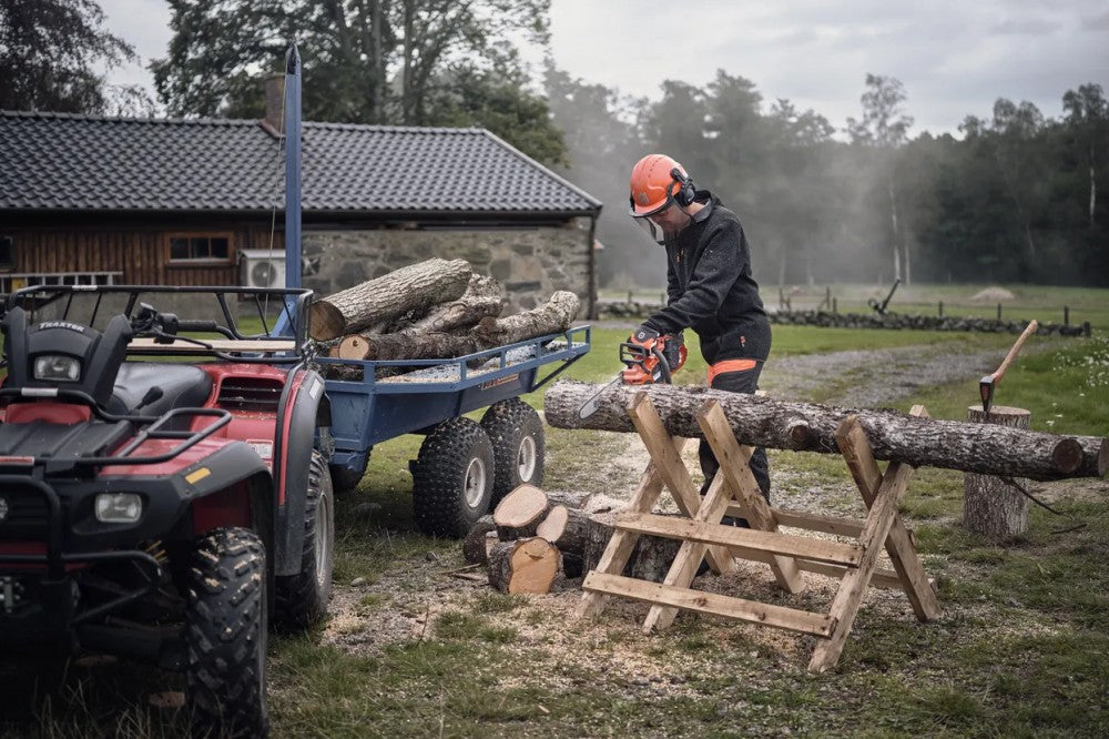 Husqvarna 340i akkus láncfűrésszel tanyaudvaron tűzifát vágó felhasználó fűrészbakon