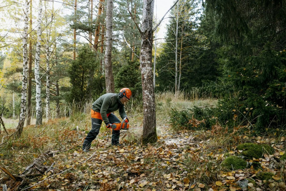 Husqvarna 340i akkus láncfűrésszel őszi erdőben dolgozó felhasználó