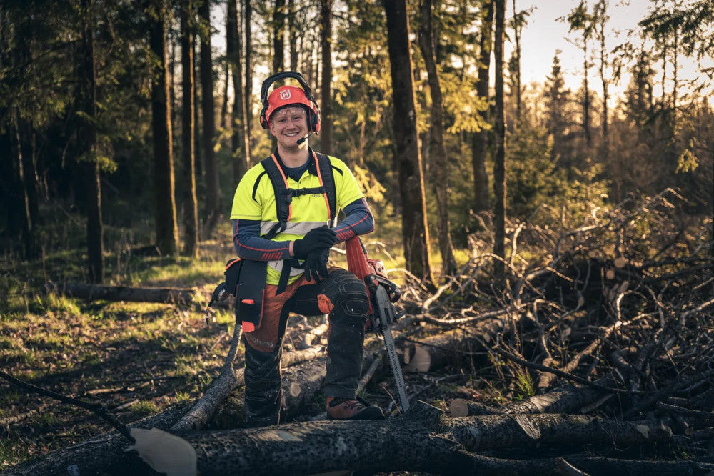 Favágó a Husqvarna 560 XP láncfűrésszel rönkön pihenve az erdőben